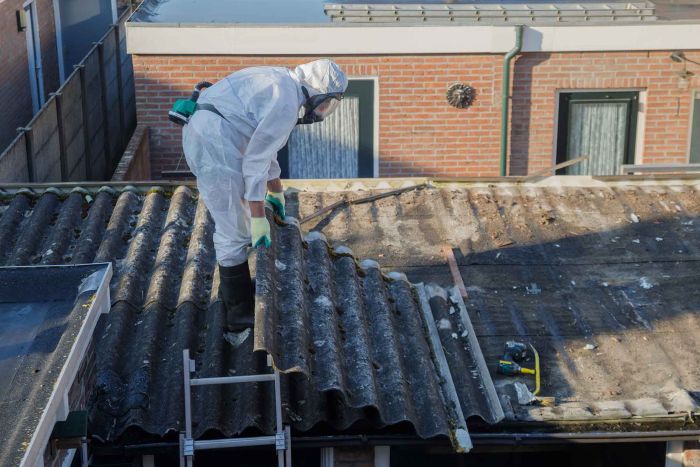 Professional asbestos removal with a man wearing protective suit.