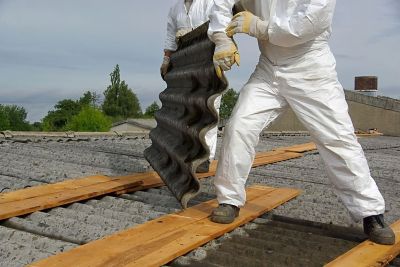 Men in white suits removing asbestos from a roof.